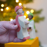 The Ostheimer Red King's Page  Three Wise Men Wooden Nativity Figure in an adult's hand. These wooden figures are part of a wide range of expertly hand crafted wooden toys here at Babipur. 