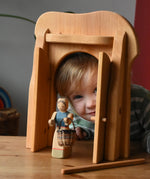 Ostheimer castle gate with a female farmer figure holding  a small Kraul basket in front. Child peering through the open doors.