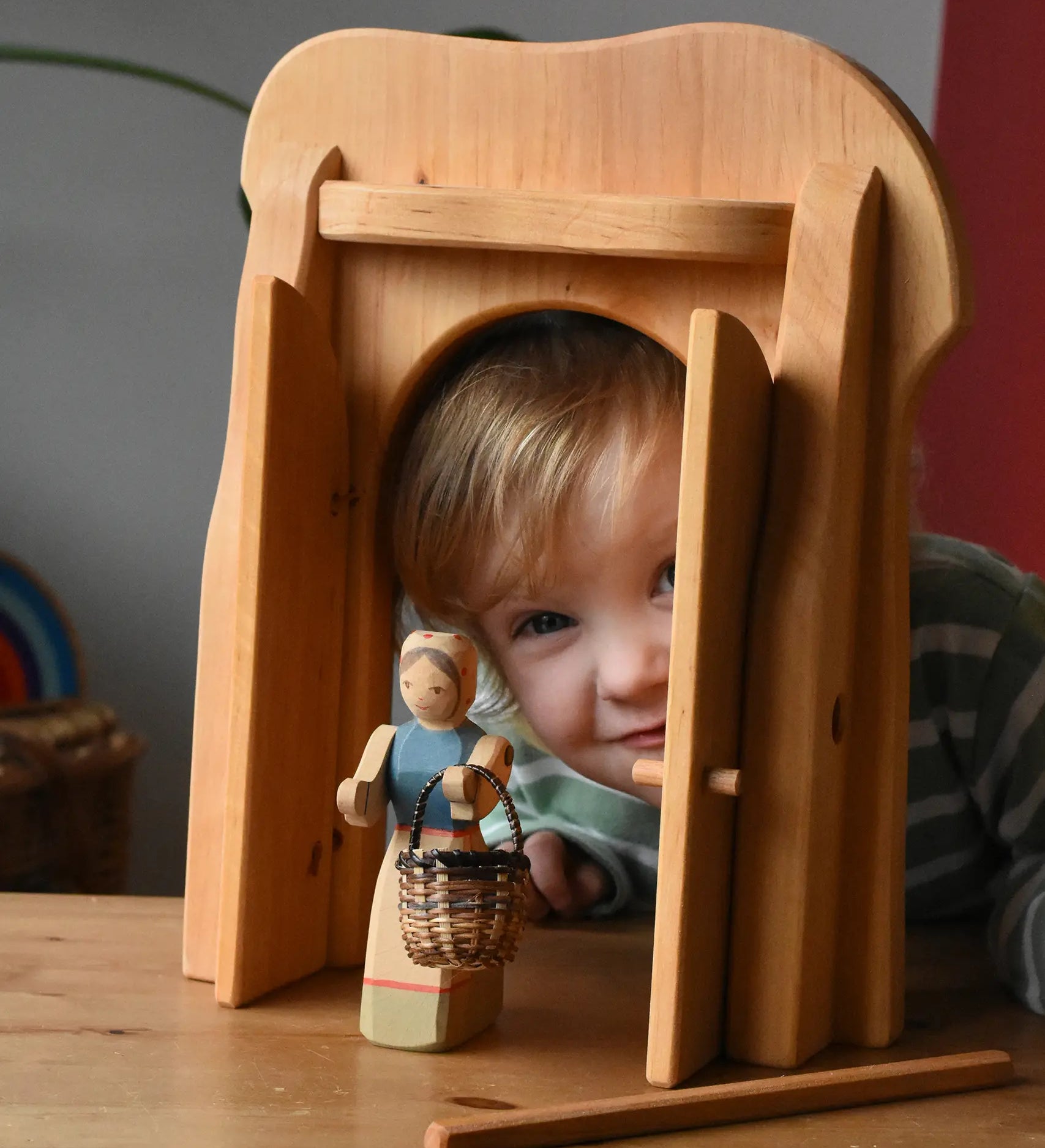 Ostheimer castle gate with a female farmer figure holding  a small Kraul basket in front. Child peering through the open doors.