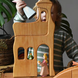 Ostheimer large wooden lookout tower wooden toy placed in a small world play scene with princess and frog king with a child placing a medival princess in the top tower.