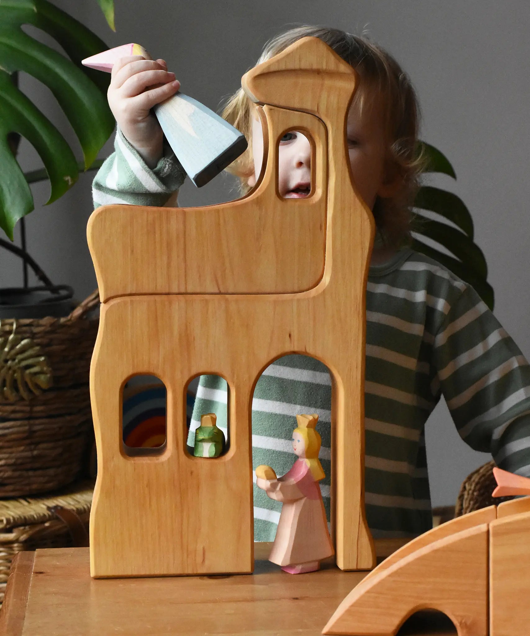 Ostheimer large wooden lookout tower wooden toy placed in a small world play scene with princess and frog king with a child placing a medival princess in the top tower.