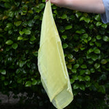 Ostheimer lemon yellow decorative play scarf held in a child's hand outdoors.