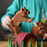 Ostheimer leopard in a child's hand resting on a mini Grimm's rainbow surrounded with green cone Grapat mandala pieces. 
