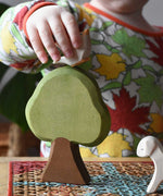 Child placing an Ostheimer dove bird figure on a Linden tree placed in a simple small world play scene.