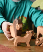 Ostheimer small lion cub with head high wooden toy figure placed on a wooden surface with a lion behind. 