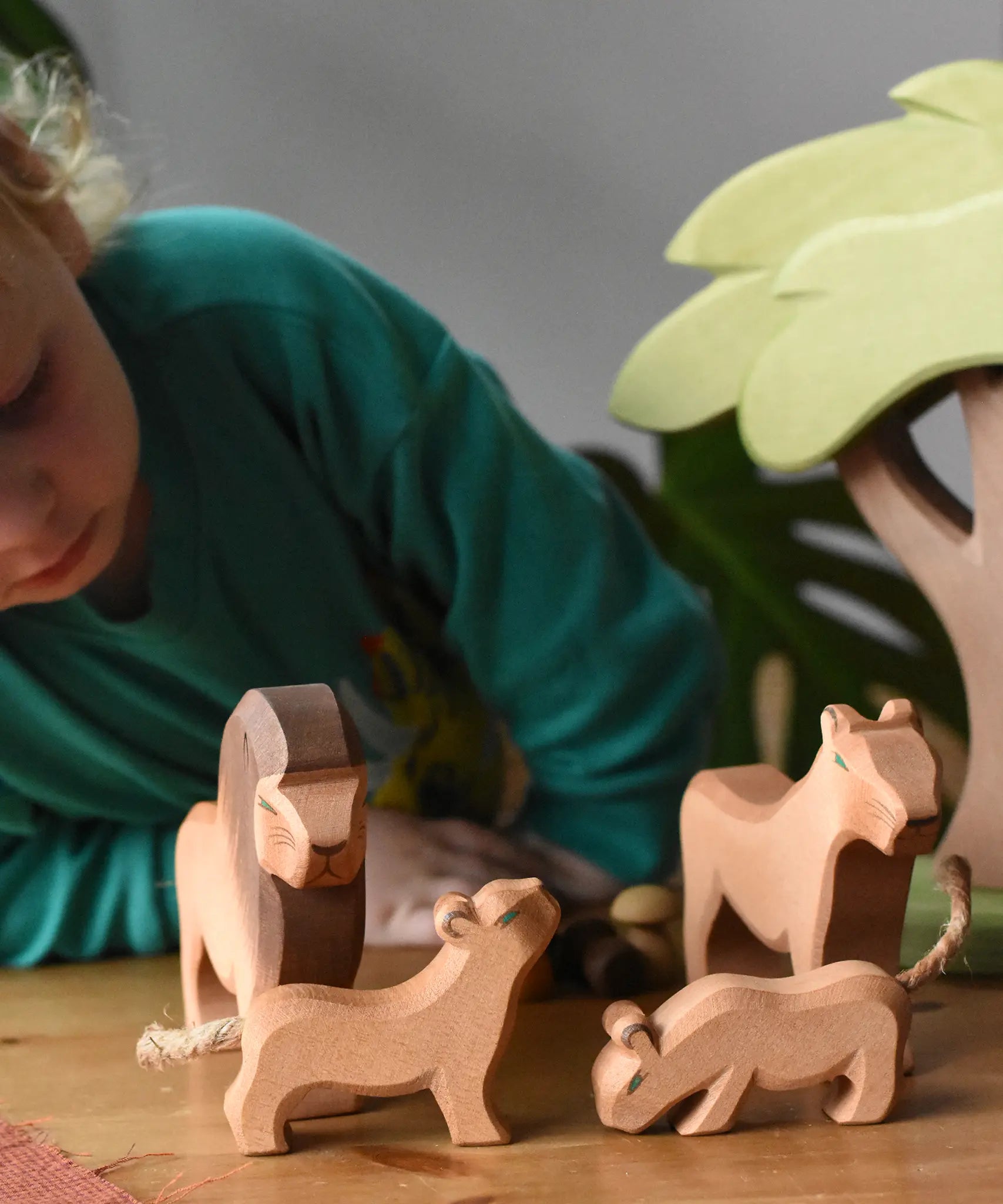 Ostheimer lion family wooden toy figures placed in a small world play scene with an African tree.