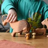 Child holding the Ostheimer male lion wooden toy figure tilting it forwards towards Grapat brown mushroom mandala pieces. 
