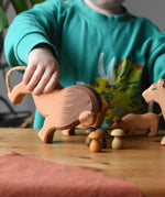 Child holding the Ostheimer male lion wooden toy figure tilting it forwards towards Grapat brown mushroom mandala pieces. 