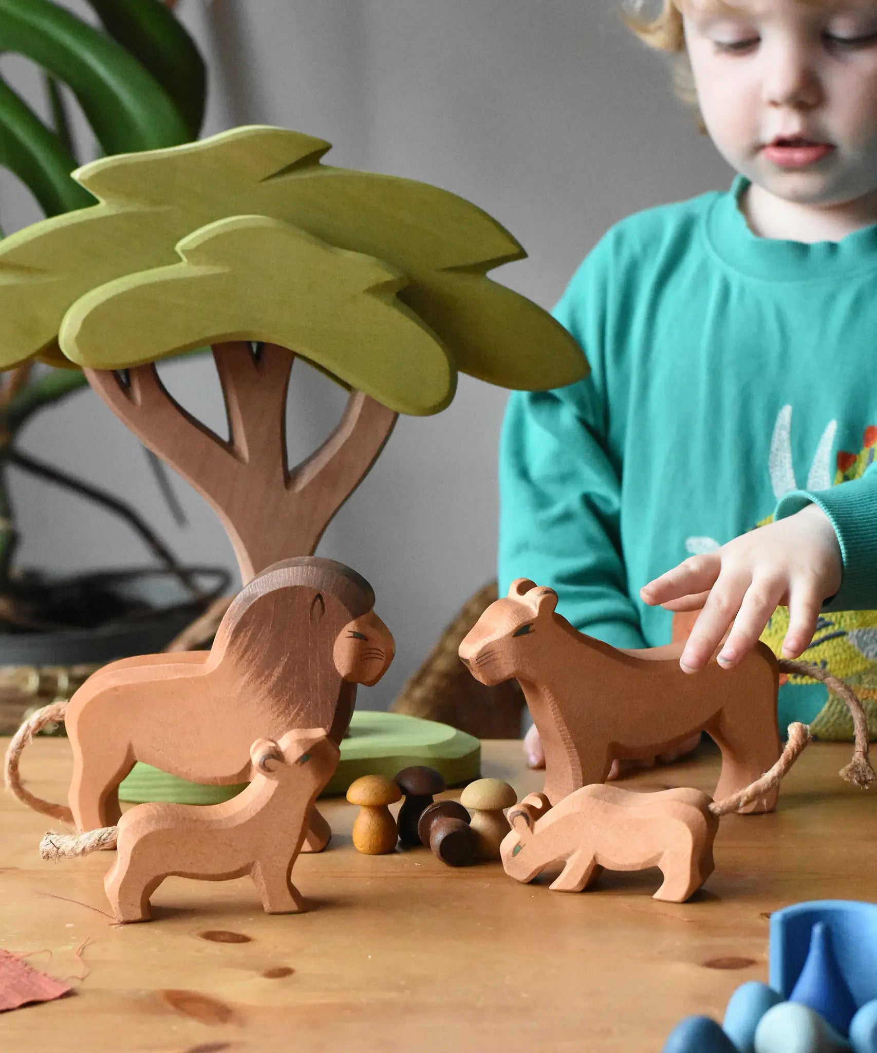 Ostheimer lion, lioness and cubs wooden toy figures placed in a small world play scene with the African tree and Grapat mandala pieces. 