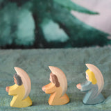 A group of three Ostheimer little angel figures placed on a green decorative cloth. There is a yellow, orange and blue coloured angel. These wooden figures are part of a wide range of expertly hand crafted wooden toys here at Babipur. 