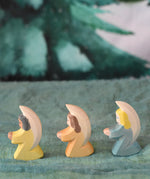 A group of three Ostheimer little angel figures placed on a green decorative cloth. There is a yellow, orange and blue coloured angel. These wooden figures are part of a wide range of expertly hand crafted wooden toys here at Babipur. 