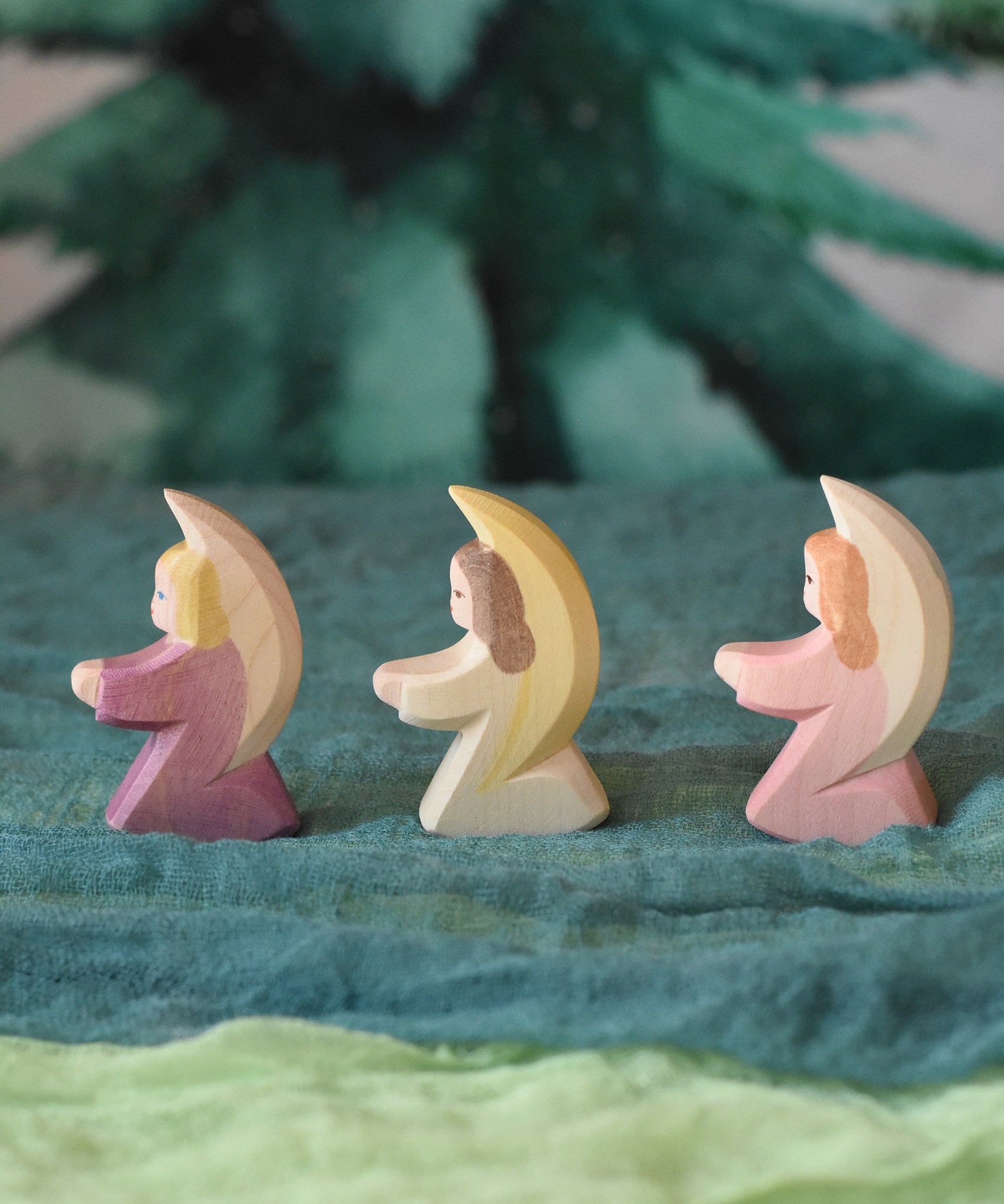 Three little Ostheimer angels lined up and placed on green coloured decorative Ostheimer scarfs. These wooden figures are part of a wide range of expertly hand crafted wooden toys here at Babipur. 
