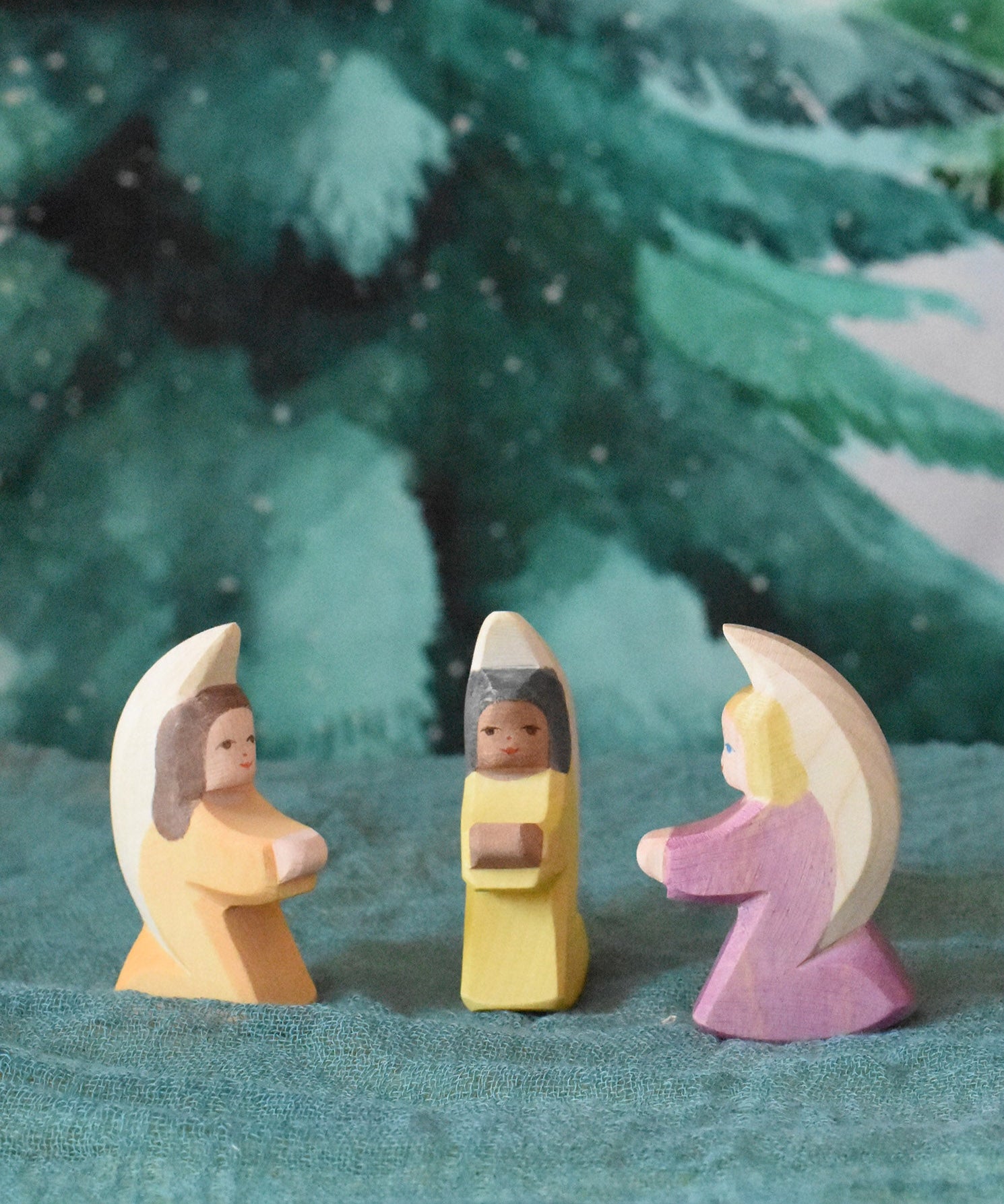 A group of three little wooden angels placed on an Ostheimer pond piece in a small world scene set up. These wooden figures are part of a wide range of expertly hand crafted wooden toys here at Babipur. 