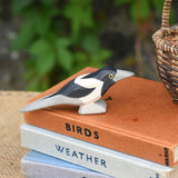 An Otheimer wooden toy magpie bird figure placed on top of a pile of books.