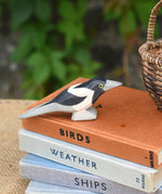 An Otheimer wooden toy magpie bird figure placed on top of a pile of books.