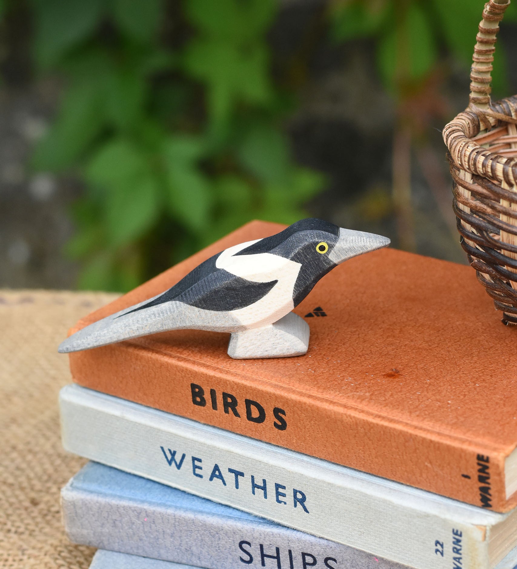 An Otheimer wooden toy magpie bird figure placed on top of a pile of books.