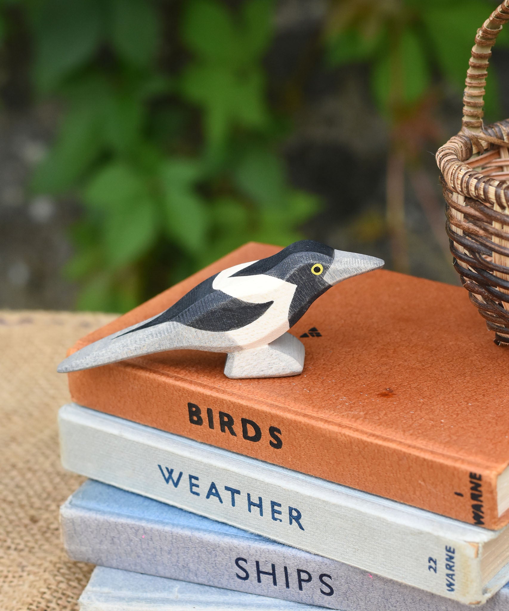 An Otheimer wooden toy magpie bird figure placed on top of a pile of books.