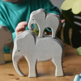 Ostheimer male elephant wooden toy figure with a small eating elephant stacked on top of it. 