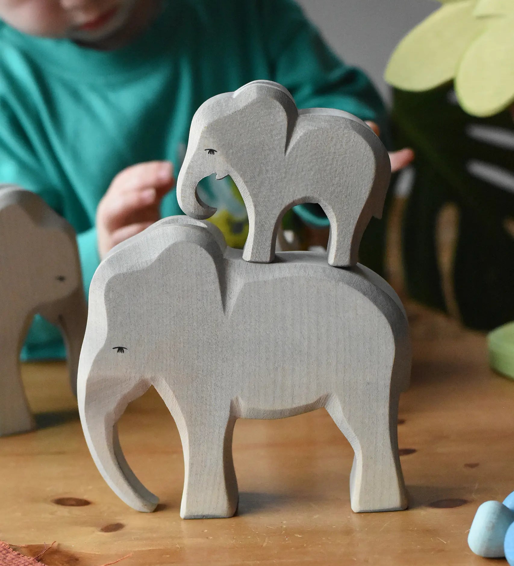 Ostheimer male elephant wooden toy figure with a small eating elephant stacked on top of it. 