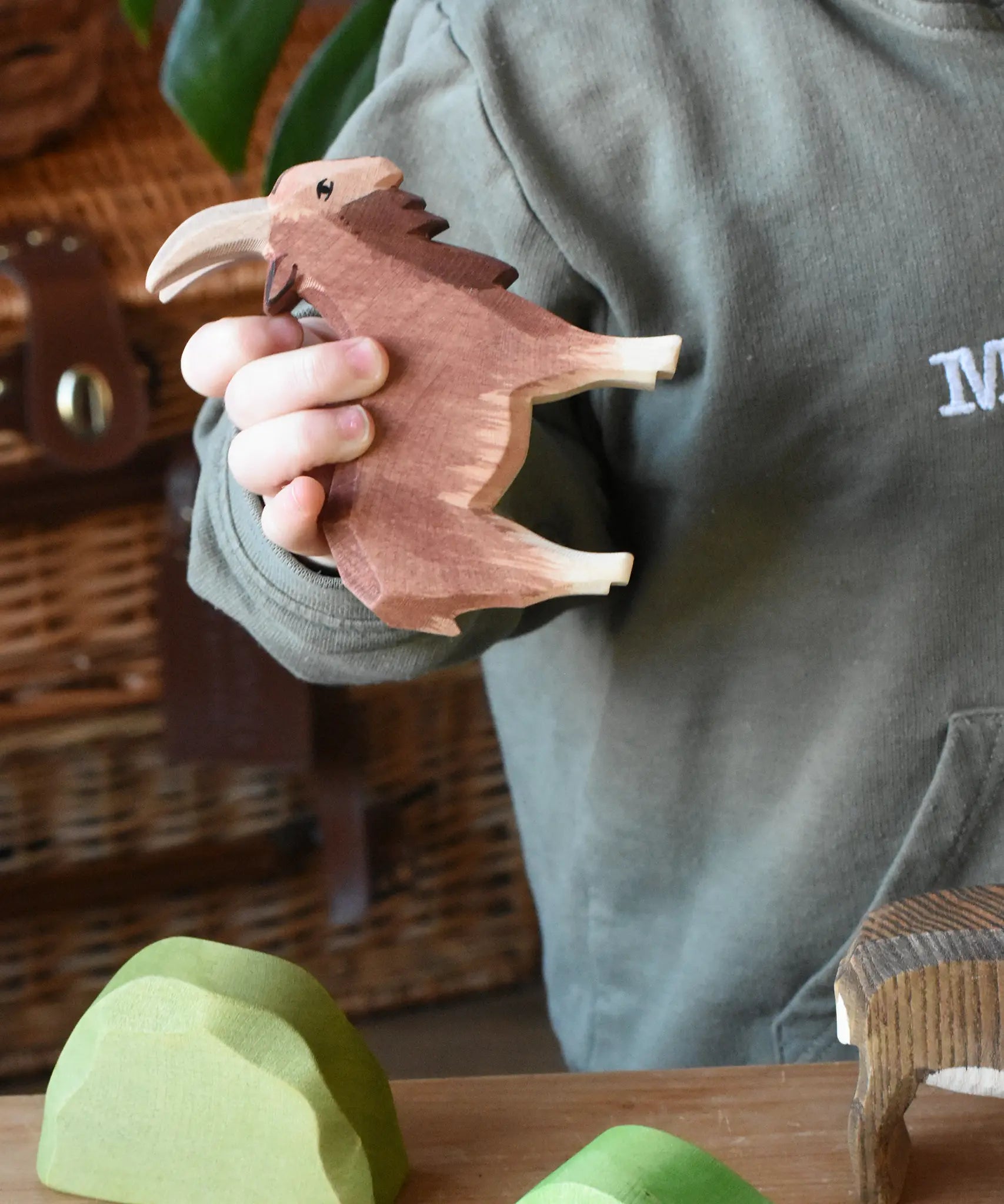 Ostheimer brown male goat wooden toy figure in a child's hand. 
