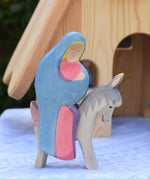 An Ostheimer Mary on donkey wooden toy figure placed in front od the fairy tale house. These wooden figures are part of a large range of expertly hand crafted, Waldorf inspired, wooden toys here at Babipur. 

