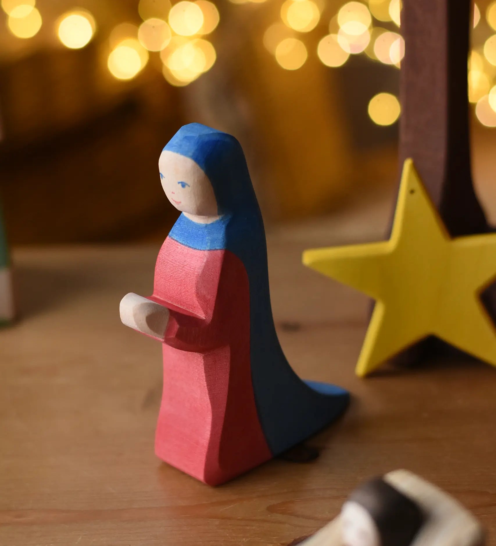 Ostheimer Mary wooden toy figure in a festive small world play scene with fairy lights in the background.