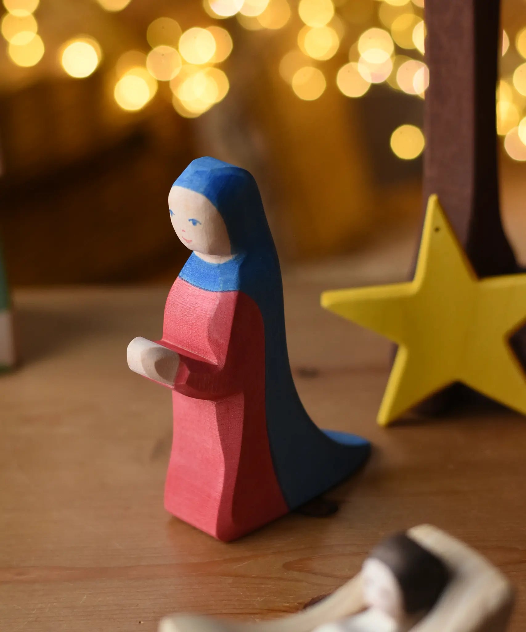 Ostheimer Mary wooden toy figure in a festive small world play scene with fairy lights in the background.