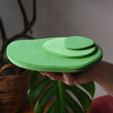 Ostheimer 3 piece meadow green base play bases stacked up on an adult's hand.