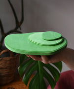 Ostheimer 3 piece meadow green base play bases stacked up on an adult's hand.