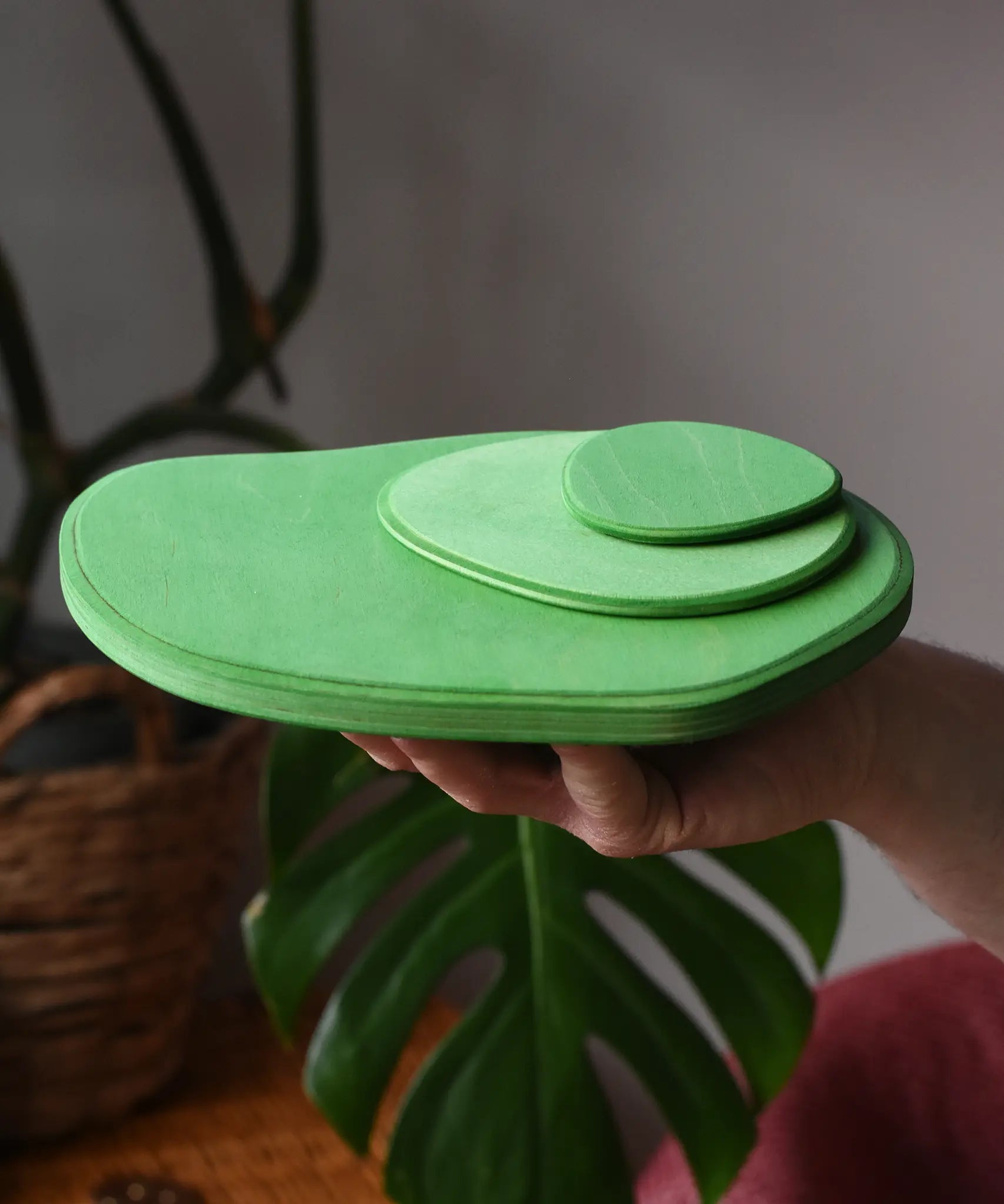 Ostheimer 3 piece meadow green base play bases stacked up on an adult's hand.