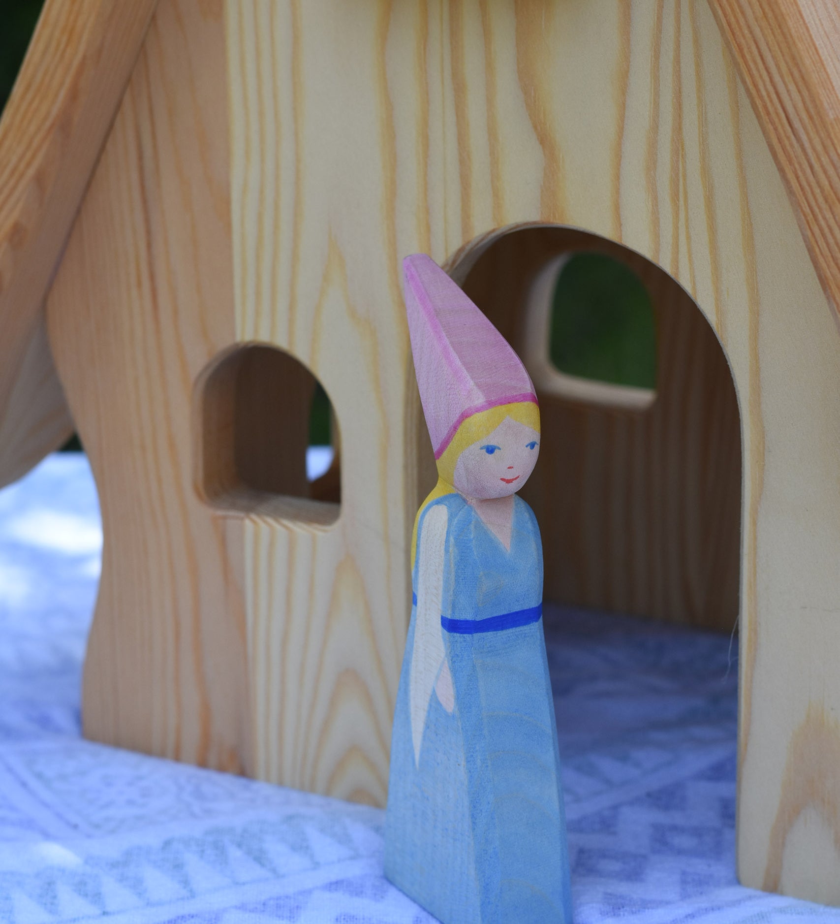 An Ostheimer Medieval Princess wooden toy figure placed in front of a Ostheimer fairy tale dolls house. This wooden figure is part of a large range of expertly hand crafted, Waldorf inspired, wooden toys here at Babipur. 