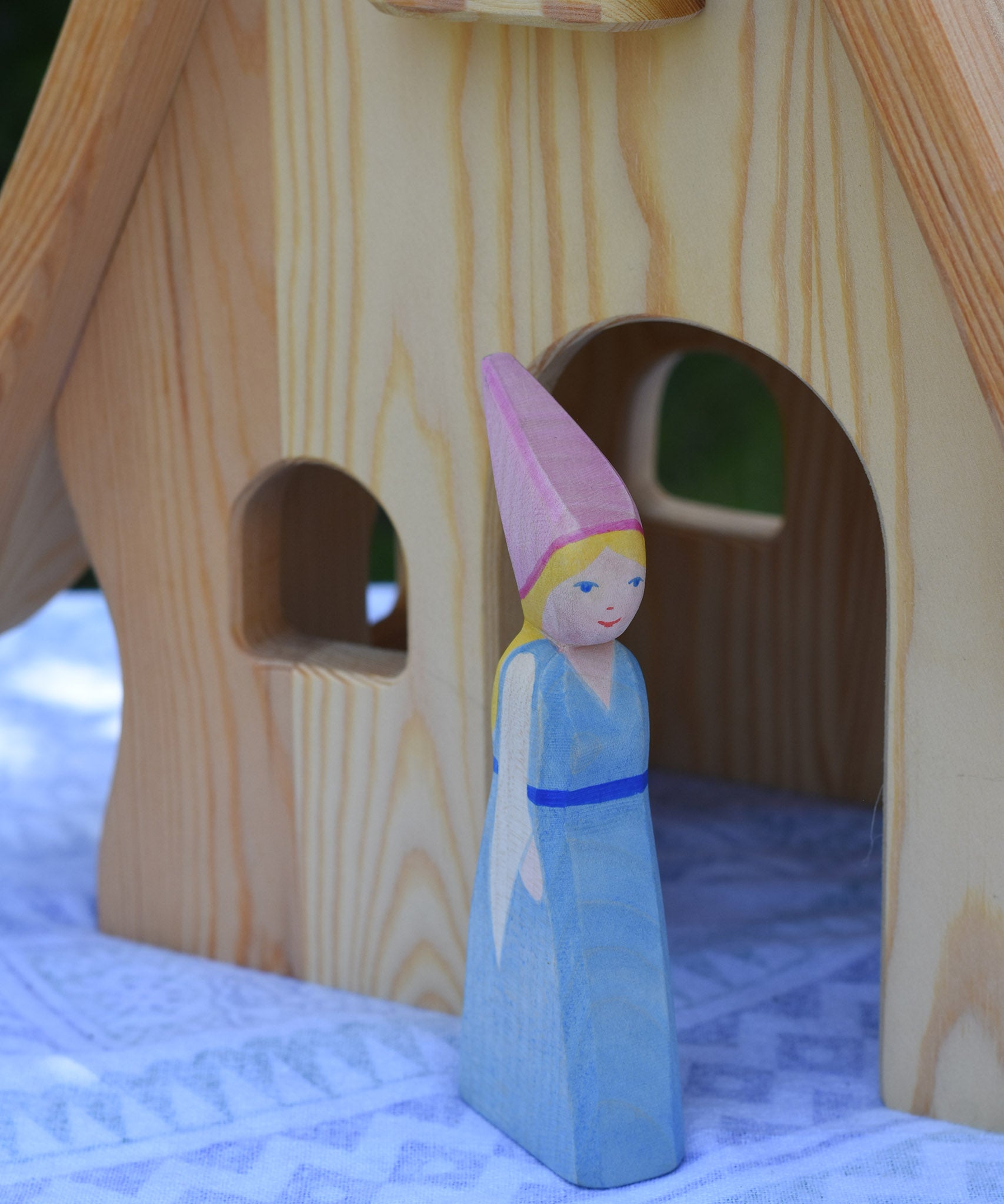 An Ostheimer Medieval Princess wooden toy figure placed in front of a Ostheimer fairy tale dolls house. This wooden figure is part of a large range of expertly hand crafted, Waldorf inspired, wooden toys here at Babipur. 