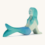 A wooden resting Ostheimer mermaid figure with blue hair on a cream background.