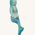 A wooden sitting Ostheimer mermaid with blue hair on a cream background.