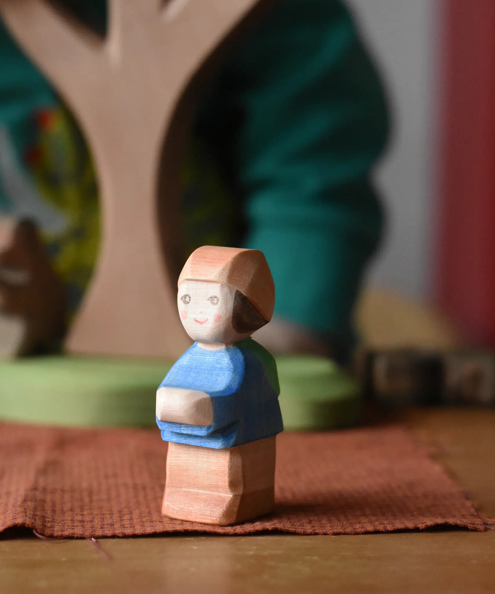Ostheimer Mo handmade little boy wooden toy figure placed on a brown cloth.