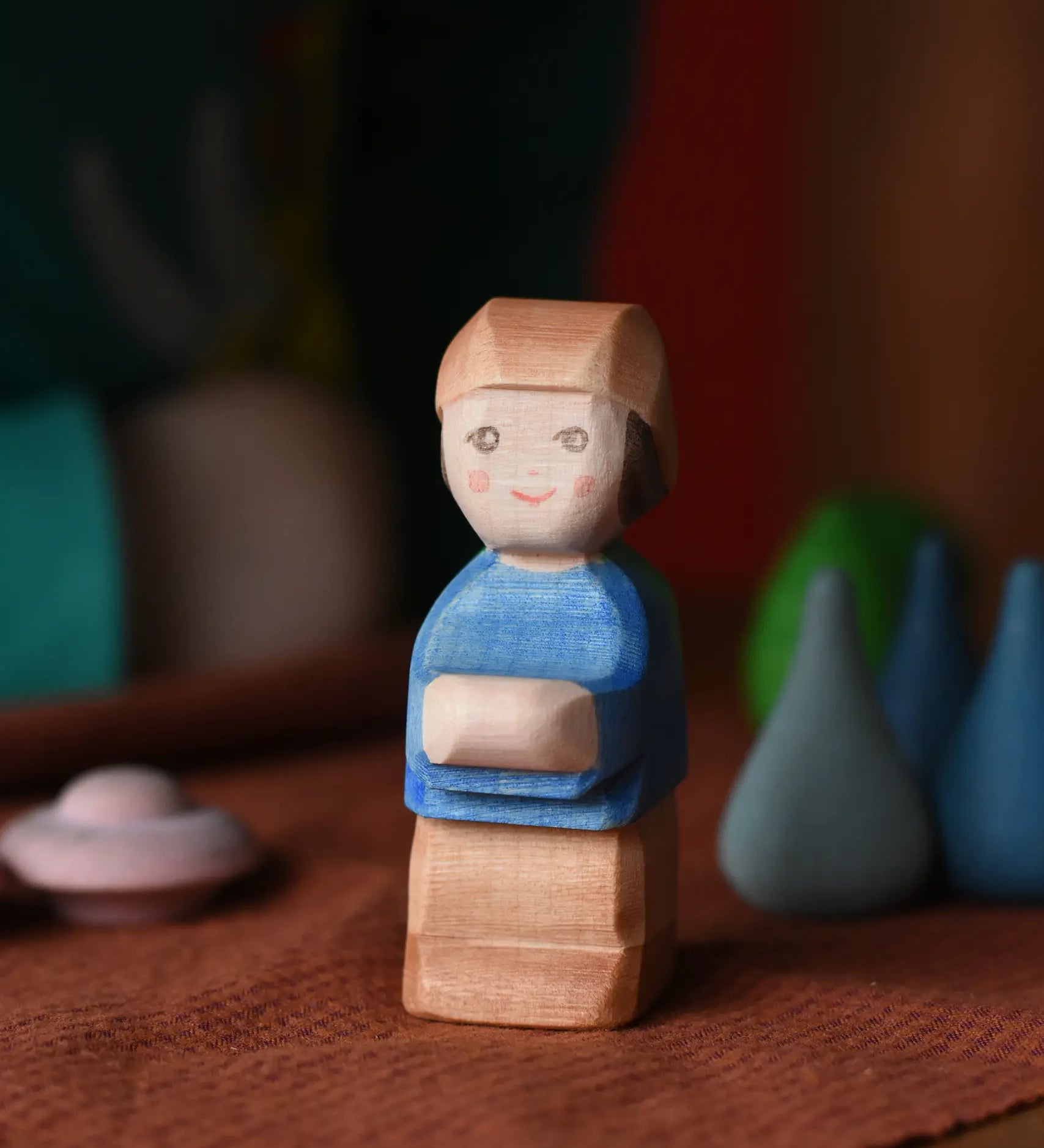 Ostheimer Mo handmade wooden toy figure. Little boy with brown trousers, blue top and a brown hat.