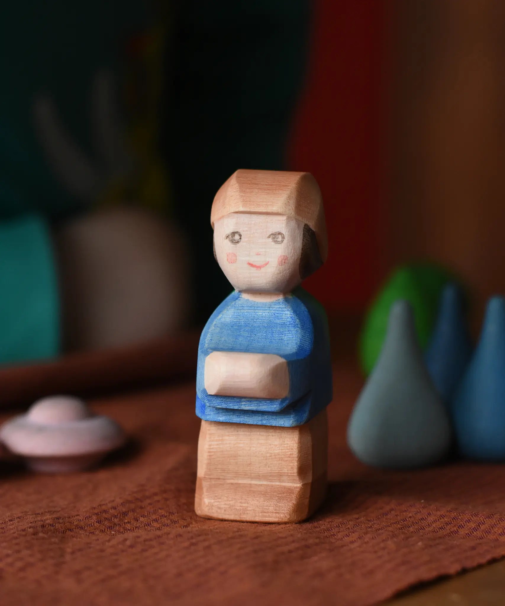 Ostheimer Mo handmade wooden toy figure. Little boy with brown trousers, blue top and a brown hat.
