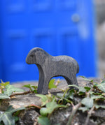 An Ostheimer wooden Moorland lamb figure placed on a stone wall outdoors. These wooden figures are part of a large range of expertly hand crafted, Waldorf inspired, wooden toys here at Babipur.