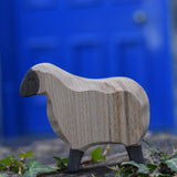 An Ostheimer moorland sheep placed on a stone wall outdoors. These wooden figures are part of a large range of expertly hand crafted, Waldorf inspired, wooden toys here at Babipur.