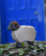An Ostheimer wooden ram figure placed on a stone wall outdoors. These wooden figures are part of a large range of expertly hand crafted, Waldorf inspired, wooden toys here at Babipur.