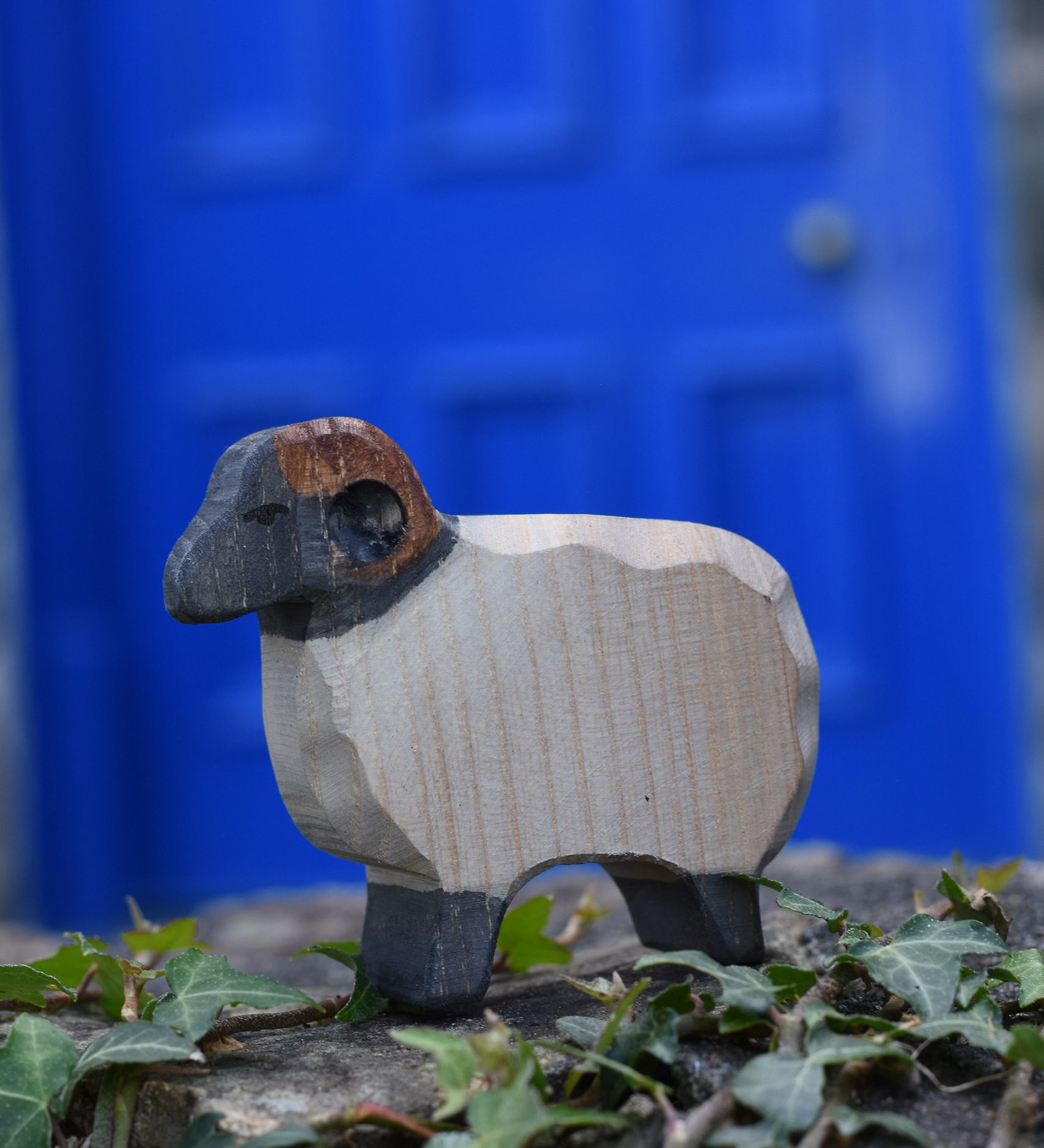 An Ostheimer wooden ram figure placed on a stone wall outdoors. These wooden figures are part of a large range of expertly hand crafted, Waldorf inspired, wooden toys here at Babipur.