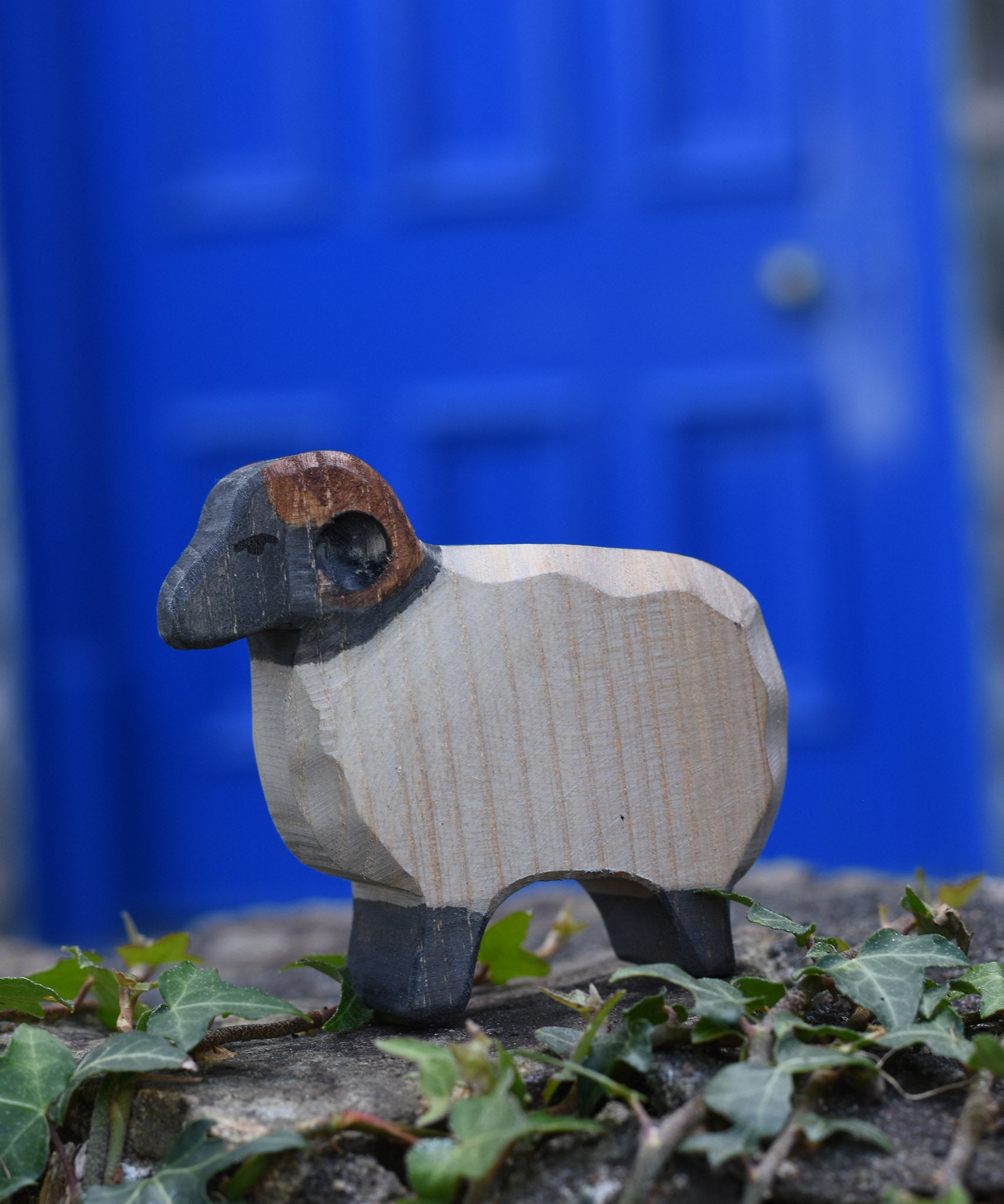 An Ostheimer wooden ram figure placed on a stone wall outdoors. These wooden figures are part of a large range of expertly hand crafted, Waldorf inspired, wooden toys here at Babipur.