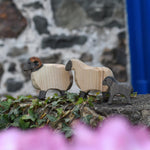 An Ostheimer wooden ram, sheep and lamb all placed on a wooden wall outdoors. These wooden figures are part of a large range of expertly hand crafted, Waldorf inspired, wooden toys here at Babipur. 