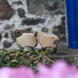 An Ostheimer wooden ram, sheep and lamb all placed on a wooden wall outdoors. These wooden figures are part of a large range of expertly hand crafted, Waldorf inspired, wooden toys here at Babipur. 