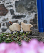 An Ostheimer wooden ram, sheep and lamb all placed on a wooden wall outdoors. These wooden figures are part of a large range of expertly hand crafted, Waldorf inspired, wooden toys here at Babipur. 