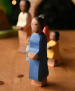 An Ostheimer mother wooden toy figure with brown skin placed at the front of a small world play scene. These wooden figures are part of a wide range of expertly hand crafted wooden toys here at Babipur.