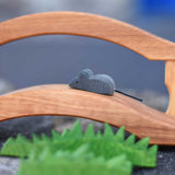 An Ostheimer mouse figure placed on a wooden toy bridge, Ostheimer wooden toy grass can be seen in the foreground of the photo. 