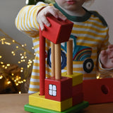 Ostheimer multi coloured block house wooden toy, child placing he blocks onto the poles.