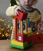Ostheimer multi coloured block house wooden toy, child placing he blocks onto the poles.