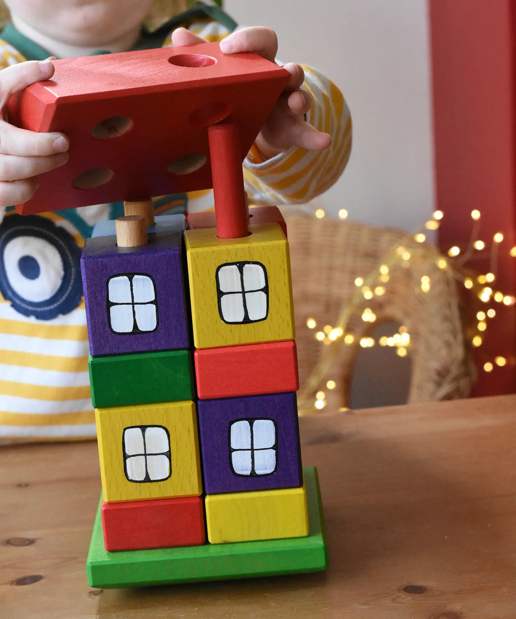 Child placing the red roof on the Ostheimer multi coloured block house.